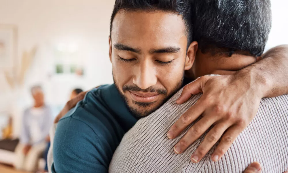 Un jeune homme enlace son père et le serre fort contre lui