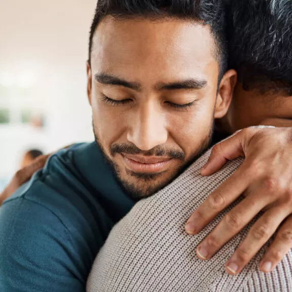 Un jeune homme enlace son père et le serre fort contre lui