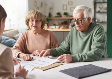 Un couple de personnes âgés semblent devoir remplir des documents administratifs