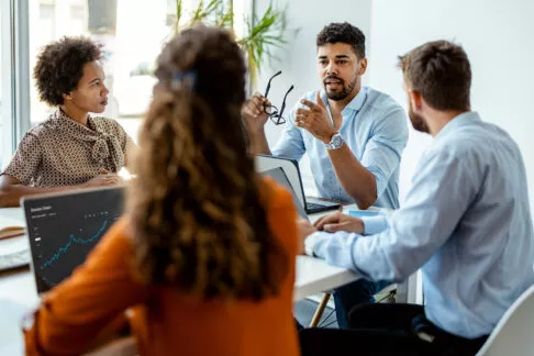 Groupe de collègues réunit autour d'une table au bureau discutant ensemble