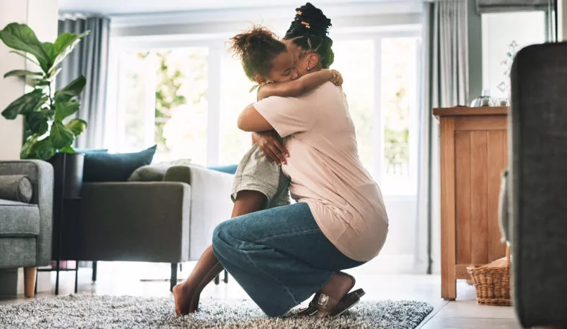 Une mère fait un câlin à sa fille dans leur salon