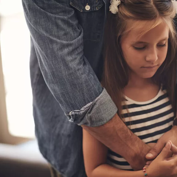 Un petite fille semblant triste, réconfortée par son père