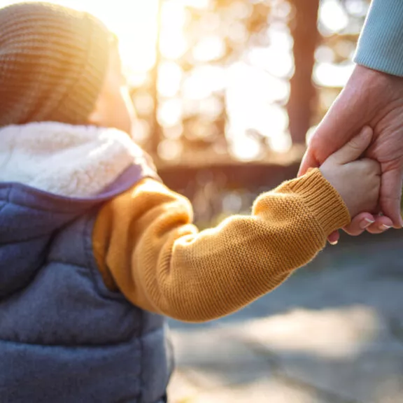 Une mère de famille tenant la main de son jeune fils lors d'un couché de soleil